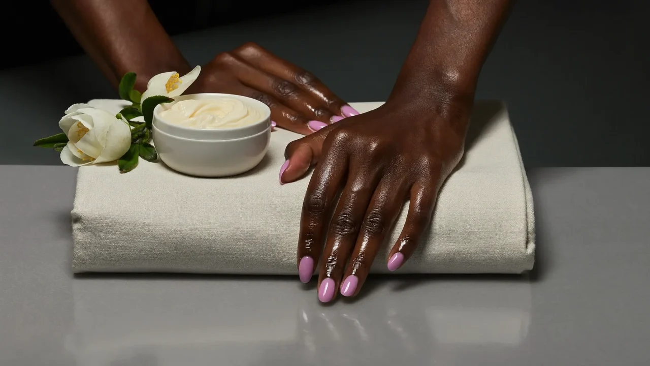 Gepflegte Hände mit glänzender Maniküre auf Leinentuch neben Handcreme (Illustration)